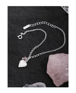 Detail of S925 sterling silver heart bracelet with pink bead on textured black background