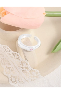 Detail of S925 silver ring with pink zircon on ceramic stand with pink tulips