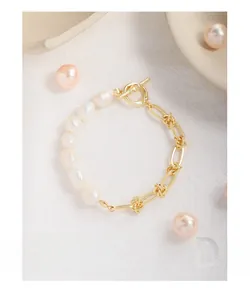 Détail du bracelet en perles baroques avec chaîne dorée et fermoir à bascule sur tissu