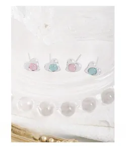 Close-up of S925 silver heart studs with pink and blue crystal on textured glass tray