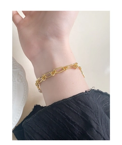 Détail d'un bracelet gourmette en or vintage avec des maillons à nœuds sur le poignet d'un mannequin