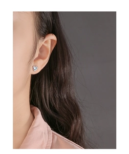 Close-up of S925 silver heart stud earrings with light blue crystal on model's ear