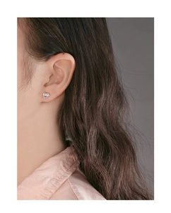 Close-up of heart-shaped pink crystal stud earring with silver s925 edge on female model