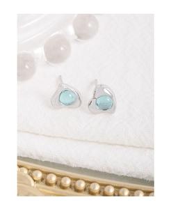 Detail of silver heart earrings with light blue crystal on white textured fabric