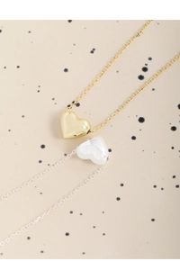 Gros plan de colliers à pendentif cœur bouffant en or et argent sur fond artistique