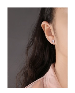 Close-up of S925 silver heart earring with purple crystal on female ear model