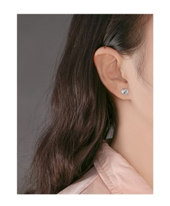 Close-up of a silver heart stud earring with crystal detail on a model's ear
