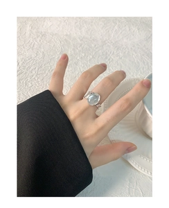 Irregular silver S925 ring with oval crystal and silver glitter on hand with coffee cup