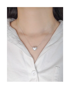 Gros plan du collier avec pendentif cœur en argent 925 porté sur une chemise blanche