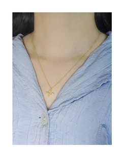 Dettaglio di una collana con ciondolo a freccia di Cupido dorata su catena sottile