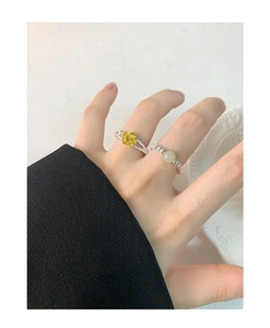Detail of silver rose flower ring and beaded green jade ring on a model's finger