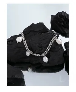 Close-up of silver Cuban chain bracelet with natural Baroque pearls on charcoal base