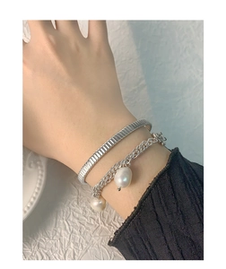 Silver textured open bangle and pearl chain bracelet set worn on wrist with elegant style