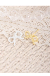 Close-up of S925 sterling silver stamp on bow-shaped earrings in gold and silver