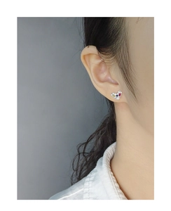 Detail of S925 silver heart stud earrings with colorful zircons worn on model ear