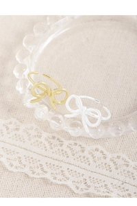 Detail of elegant bow-shaped open rings in gold and silver finish on white lace