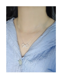 Detail of S925 sterling silver bow pendant necklace worn on neck with striped shirt
