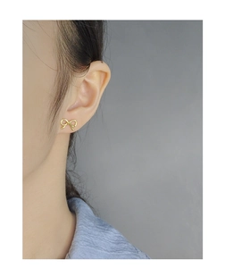 Close-up of elegant gold bow stud earrings worn on model for a dainty minimalist look