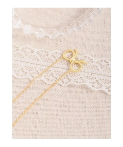 Close-up of elegant gold hollow bow pendant necklace on a delicate lace background
