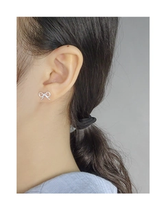Close-up of a silver S925 bow stud earring worn by a model with a polished finish