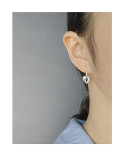 Macro side view of minimalist S925 sterling silver heart-shaped drop earrings on model