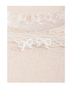 Close-up of S925 sterling silver hollow bow earrings on textured beige lace background