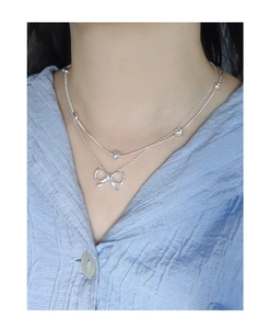 Close-up of S925 sterling silver layered necklace with hollow bow pendant on a model