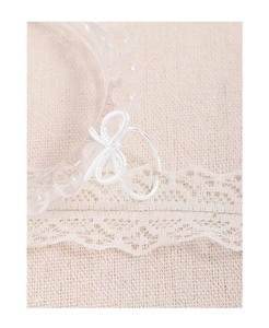 Close-up of a silver bow ring with polished finish on a lace and linen background