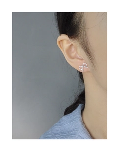 Close-up of minimalist S925 sterling silver bow knot stud earrings on a model's ear