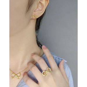 Three-piece gold hollow bow jewelry set including necklace, earrings, and ring on model