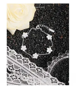Détail macro du bracelet en argent S925 avec breloques fleurs blanches à cinq pétales