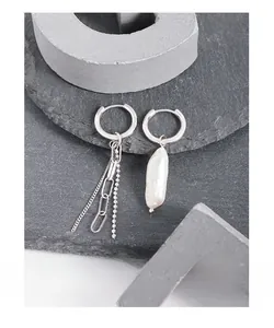 Detailed view of silver asymmetrical earrings with tassel chains and baroque pearl charm