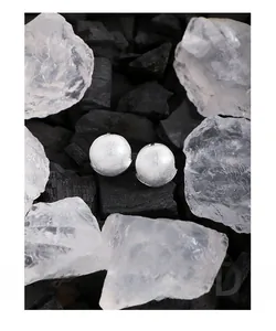 Macro view of brushed silver ball earrings featuring a unique folded rim design