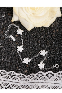 Gros plan d'un bracelet en argent S925 avec breloques fleurs sur fond de pierres noires