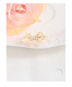 Detailed view of a gold bow ring with white pearls and a central square zircon