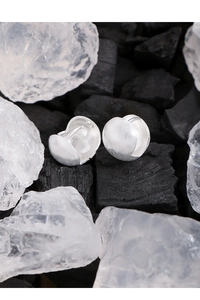 Close-up of S925 sterling silver brushed ball earrings on charcoal and crystal