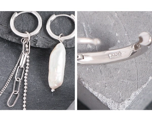 Macro detail of asymmetric S925 silver earrings with baroque pearl and tassel chain links