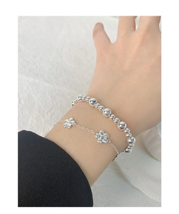 Gros plan d'un ensemble de bracelets en argent S925 avec breloque fleur 3D au poignet
