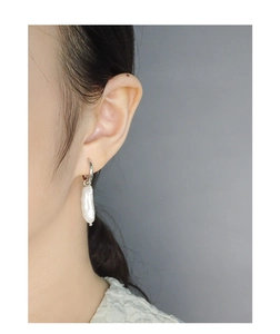 Close-up of minimalist silver hoop earring with an irregular baroque freshwater pearl