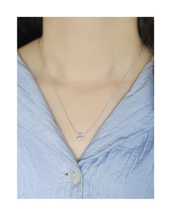 Détail d'un collier pendentif cerise en argent S925 sur un mannequin en chemise bleue