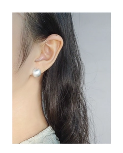 Close-up of S925 sterling silver ball stud earrings with brushed texture on ear lobe
