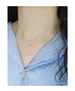 Gros plan d'un collier triple rang en argent S925 avec pendentif flèche et perles sur modèle