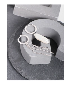Detail shot of asymmetric silver earrings with Baroque pearl and multi-strand chains