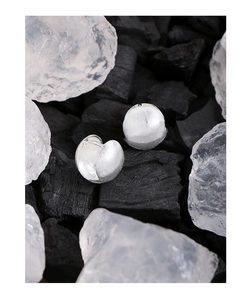 Macro detail of S925 sterling silver ball earrings featuring a matte brushed metal finish