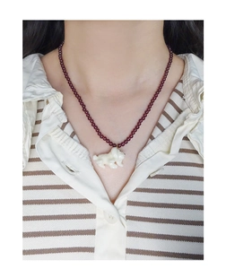 Detail of red garnet beaded necklace featuring a 3D white dog pendant on model