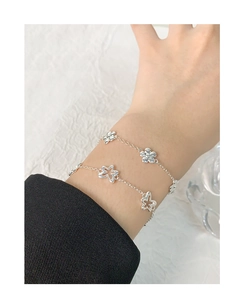 Gros plan d'un bracelet double couche en argent S925 avec breloques fleurs au poignet