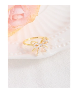 Detailed close-up of a gold bow ring with micro pearls and a center zircon stone