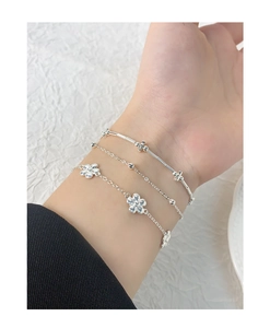 Gros plan d'un ensemble de trois bracelets argentés avec charms de fleurs