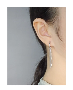 Detailed view of silver dangle earrings with bead and paperclip chain fringe on a model