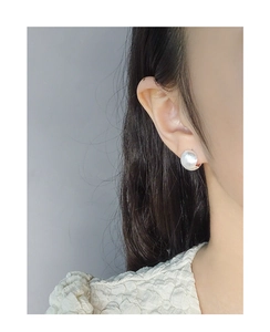 Close-up of matte silver ball stud earrings with brushed texture on model's ear